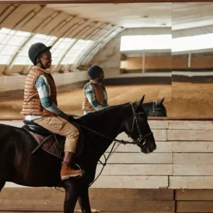 Riding arena with mirror sheets on the side walls for visual control of rider and horse